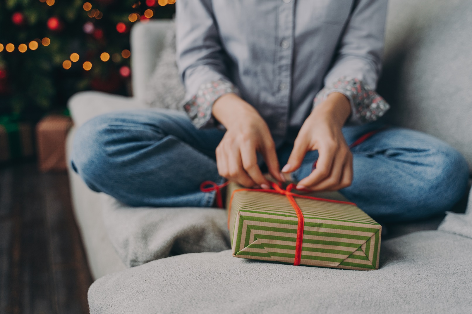 Cropped shot of woman opening wrapped christmas gift box at home during winter holidays